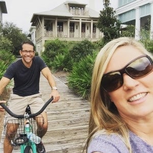 Man and woman riding bikes on beachside walkover