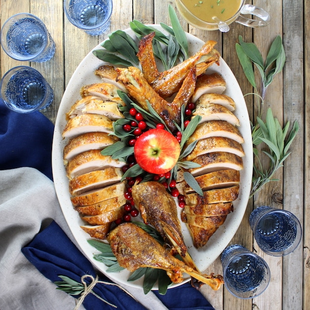 Full turkey carved and arranged on serving platter with blue glassware and blue napkins
