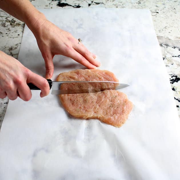 Cutting uncooked chicken breast in half 