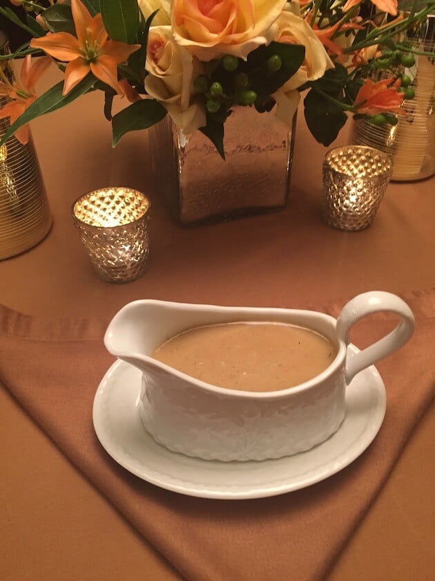 Turkey gravy in white gravy boat on Thanksgiving dinner table