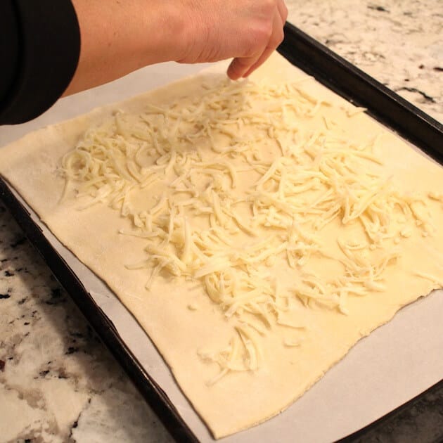 Sprinkling cheese on puff pastry dough
