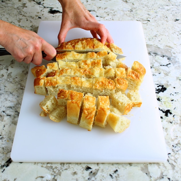 Cutting up asiago cheese bread for turkey stuffing