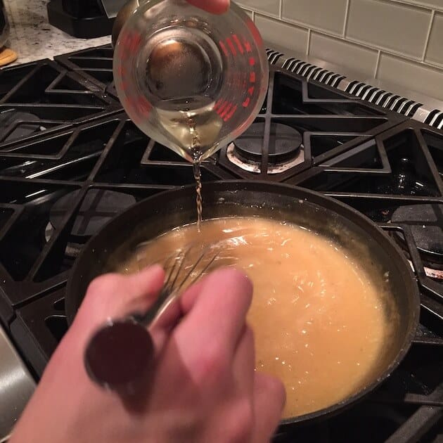 adding white wine into saucepan for turkey gravy