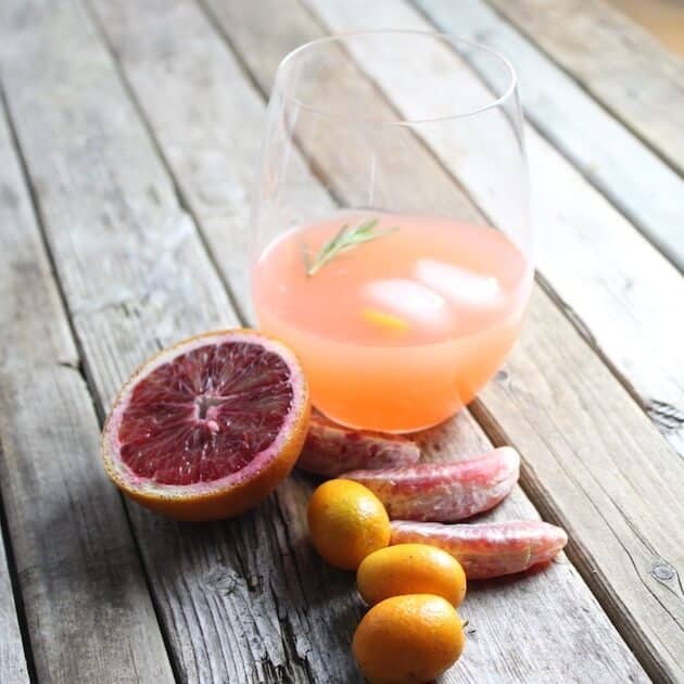 Aperol Punch glass on farm table with citrus garnishes