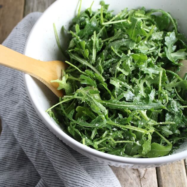 partial bowl of Arugula Salad With Parmesan &amp; Lemon on table