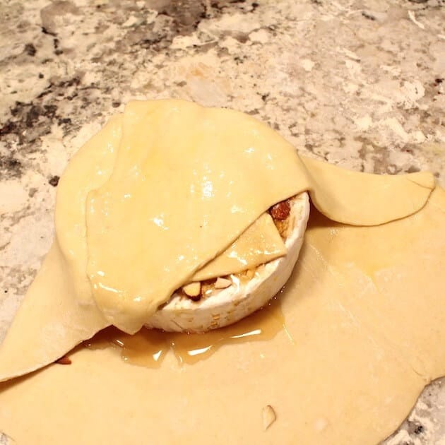 Wrapping a brie round in dough and brushing it with egg wash. 