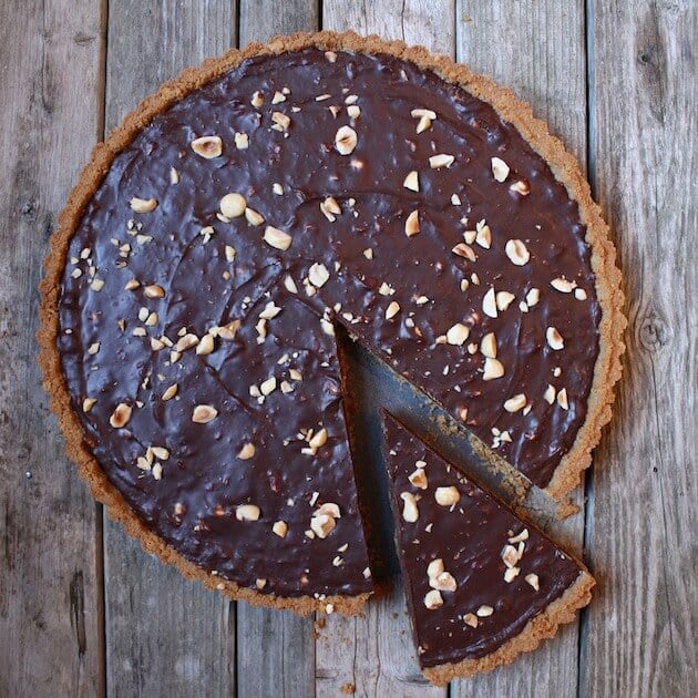 Chocolate Hazelnut Tart on farm table with slice partially removed 