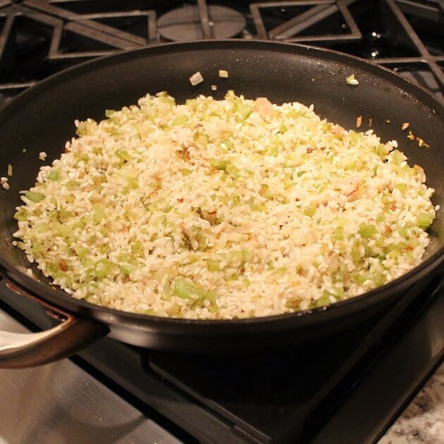 Celery and onions with arborio rice cooking in saute pan