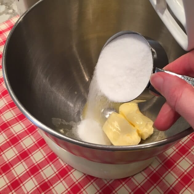 Pouring sugar into mixing bowl with butter on an electric stand mixer