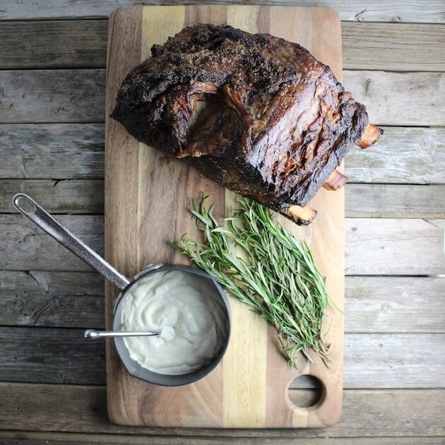 Standing rib roast on cutting board with rosemary and horseradish sauce