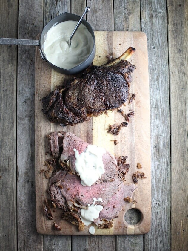 Standing Rib Roast Slices on a cutting board with cream sauce