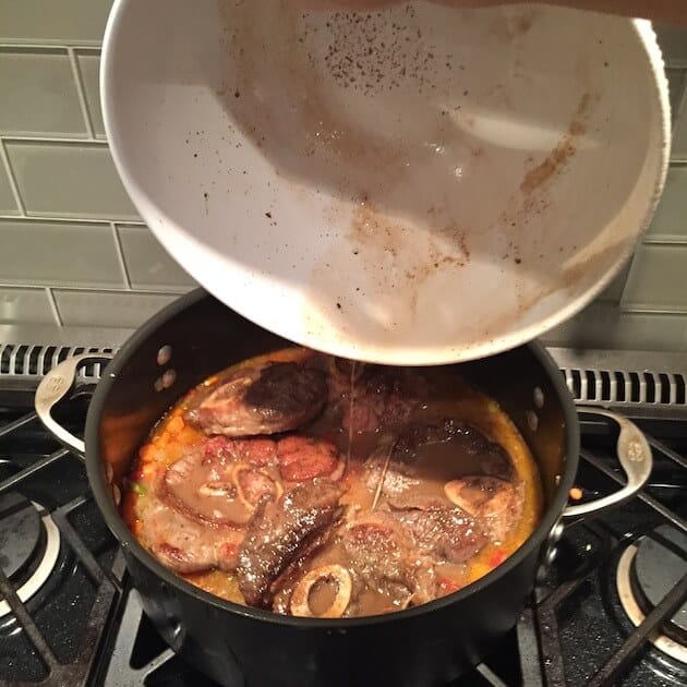 Veal Osso Buco Pan juices pouring into Dutch Oven