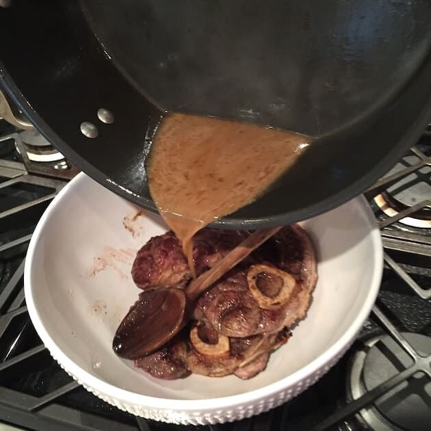 Pouring the juices into the bowl after searing.