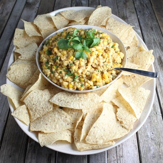 Bowl of Creamy Cheesy Corn Dip with corn chips on serving platter