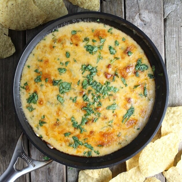 Queso fundidio in a skillet with cilantro & onion garnishes