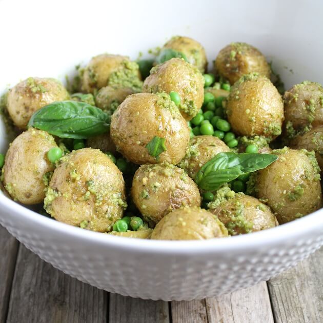 Potato Salad with pesto, peas, and basil in white serving bowl