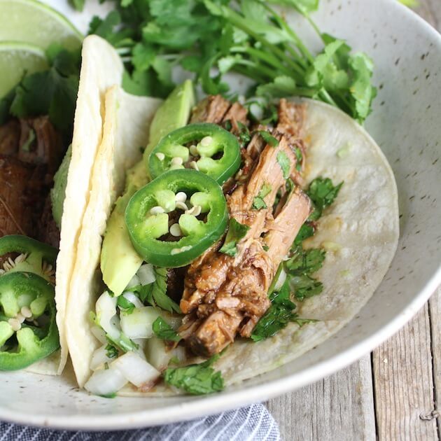 Close up of soft taco with beef barbacoa, jalapeno, onion, &amp; avocado 