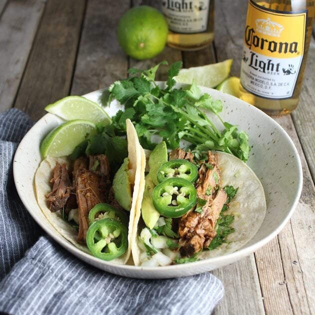 Slow Cooker Beef Barbacoa taco and corona beer in background