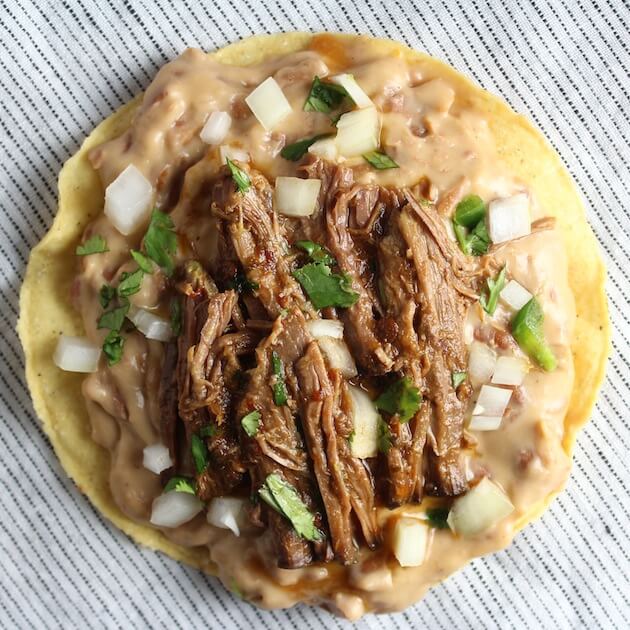 Beef Barbacoa on refried beans and crunchy tostata