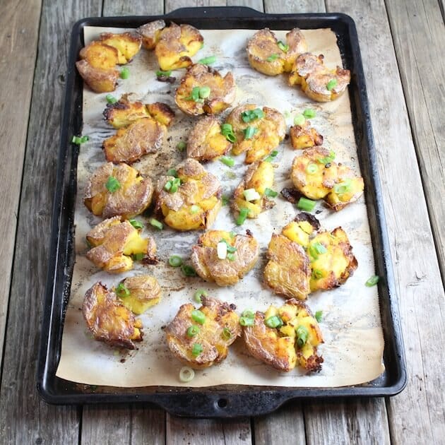 Cookie sheet full of small potatoes baked then Smashed flat Potatoes