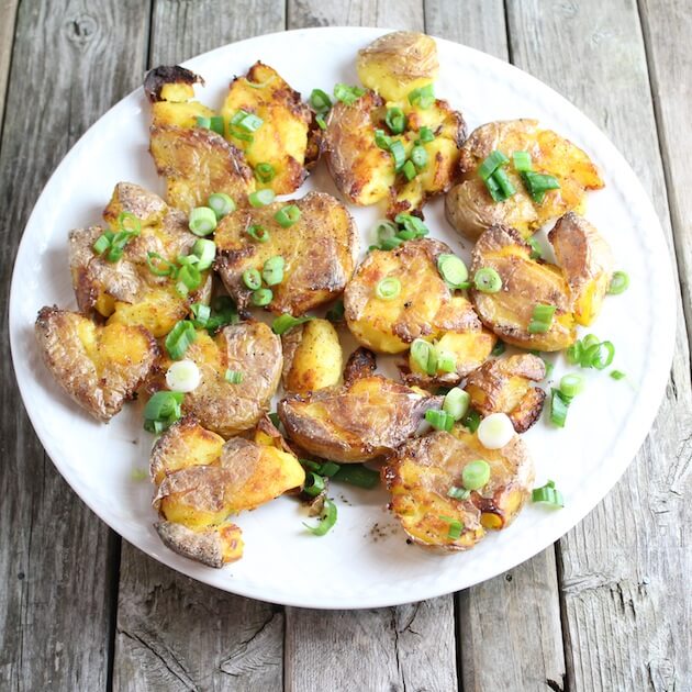 Smashed Potatoes on a plate after 2nd cooking, with green onions