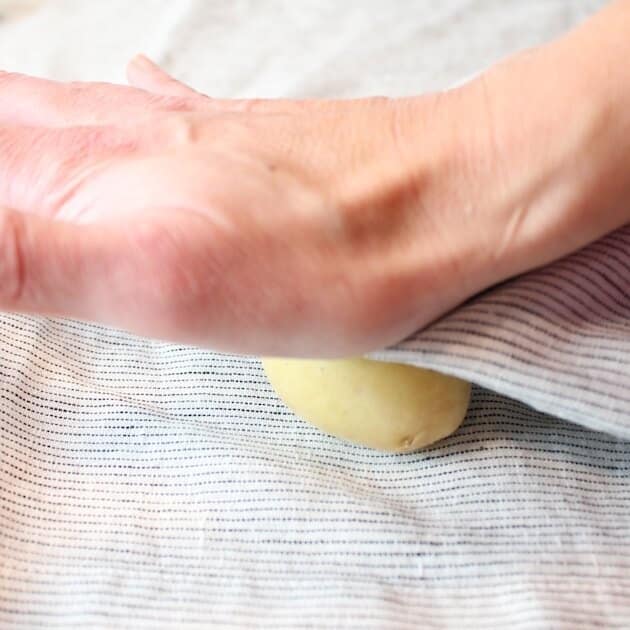 Hand smashing a small potato in a napkin 