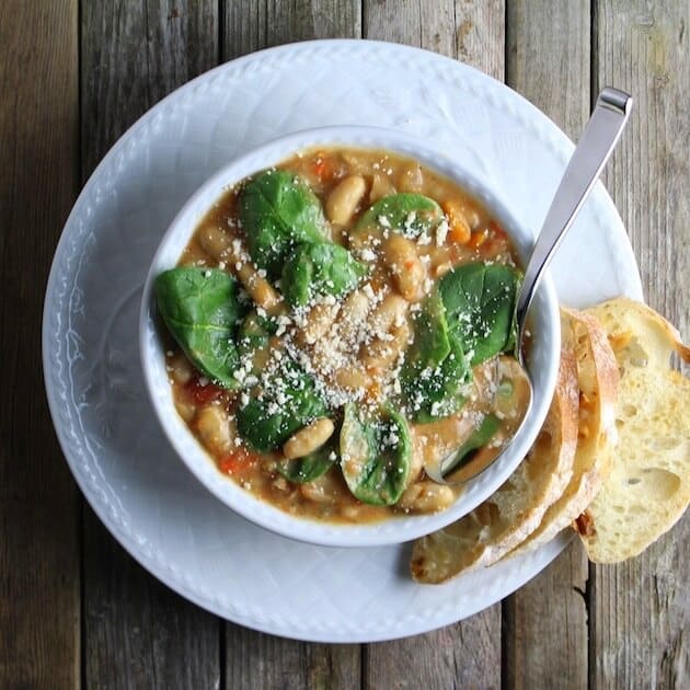 Spicy Italian White Bean and Sausage Soup bowl  on a plate with toasted crostini 