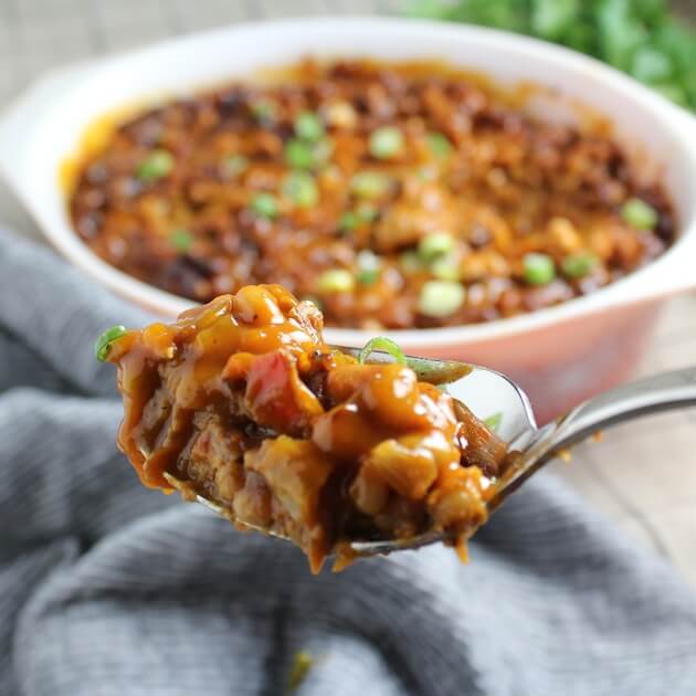 Spoonful of BBQ Baked Beans with serving dish in background