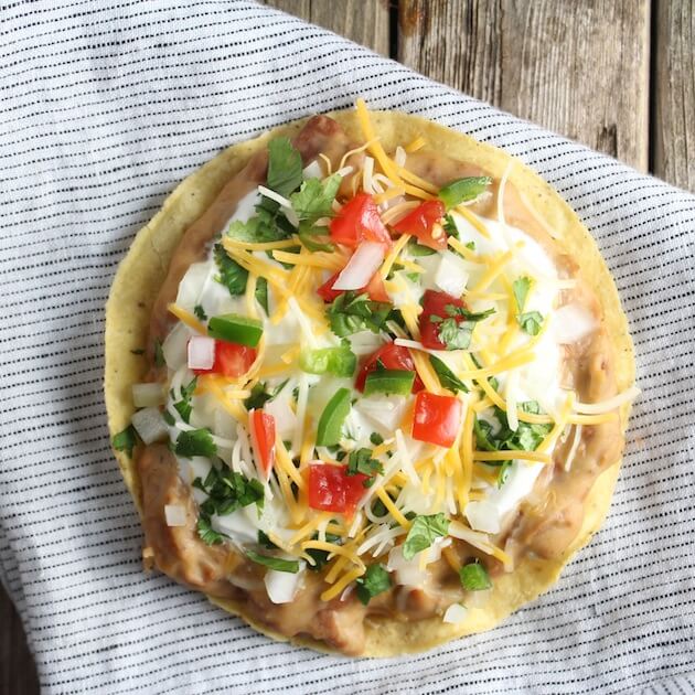 Mexican Pizza on napkin with refried beans, onions, sour cream, tomatoes, and jalapeno