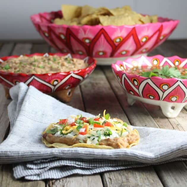 Crunchy Mexican Pizza on a napkin with bowls of chips, beans, and salsa