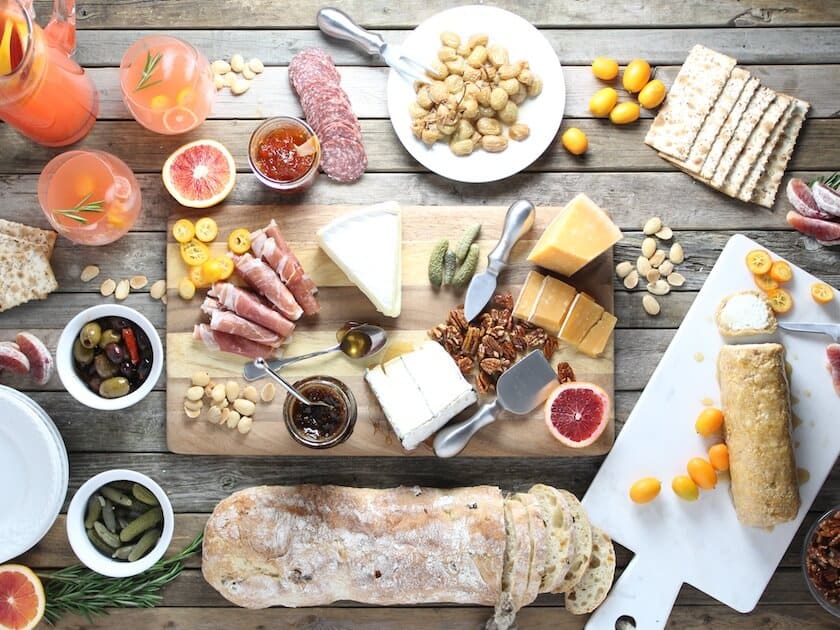 Cheese Board with many nuts, cheeses, meats, olives, pickles, crackers, and bread