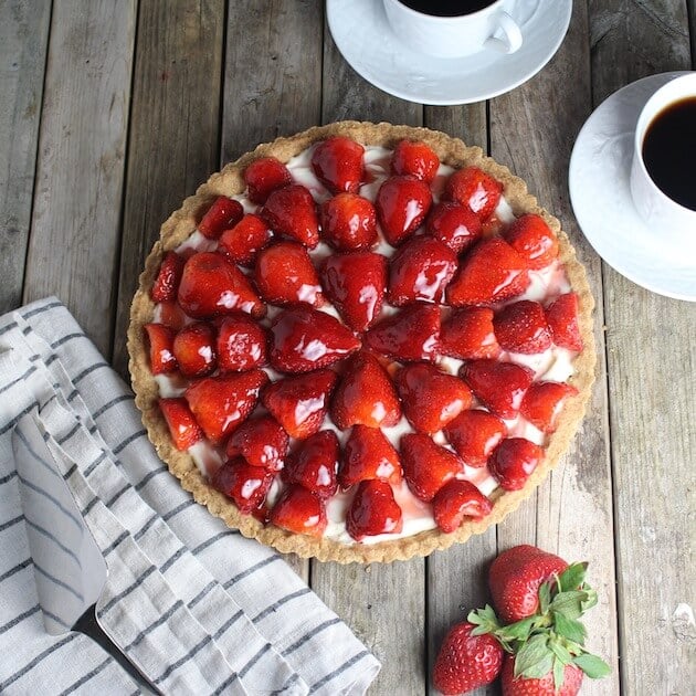 Strawberry Mascarpone Tart on table with mugs of coffee and napkin