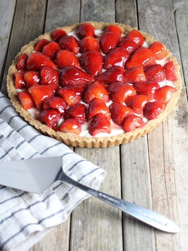 Strawberry Mascarpone Tart on farm table with spatula