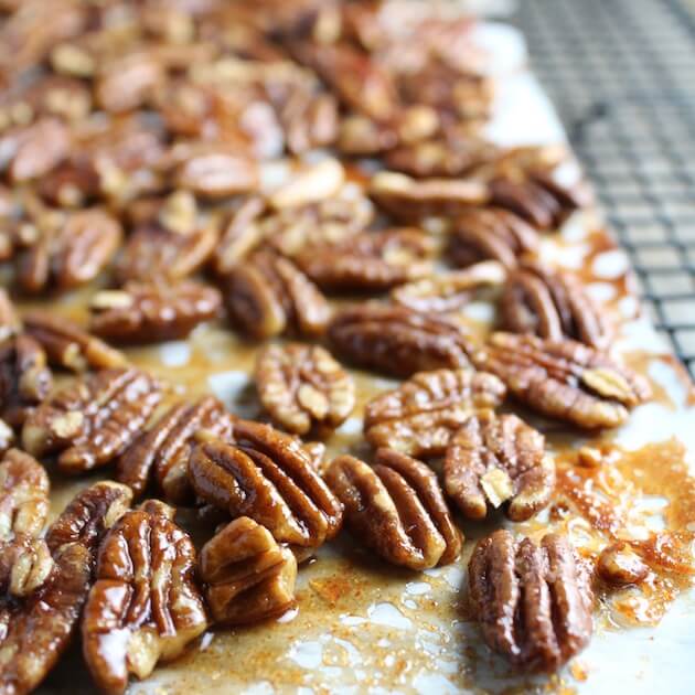 Candied baked pecans on parchment on wire rack