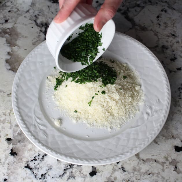 Adding chopped parsley to plate of grated Parmesan cheese 