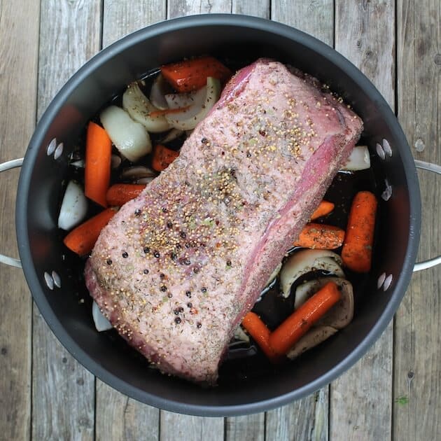 Whole corned beef with pickling spices in dutch oven before cooking