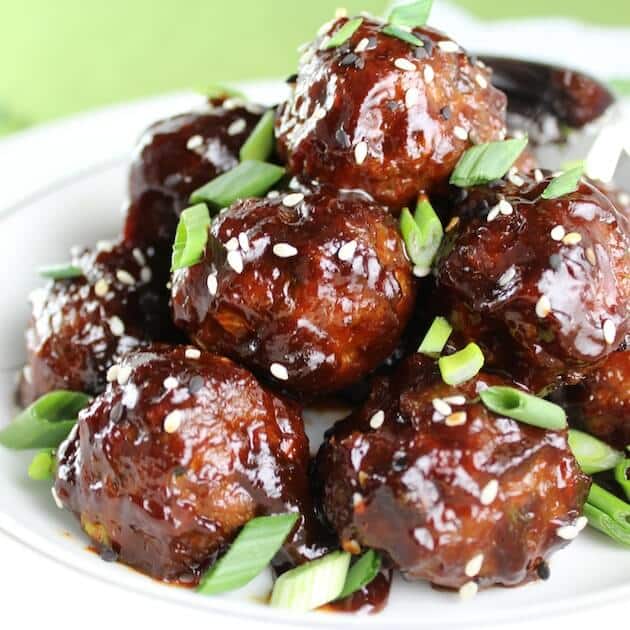 Meatballs stacked on a plate with sesame seeds and green onions