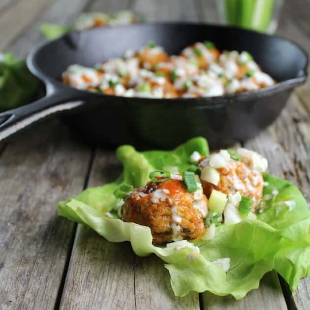 Lettuce wrap with Buffalo Chicken Meatballs on a farm table with skillet in background