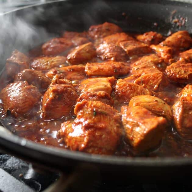 Moroccan Chicken simmering in skillet on stovetop.