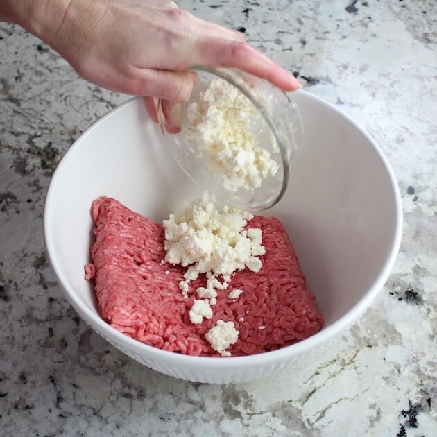 Adding feta to lamb meat in mixing bowl