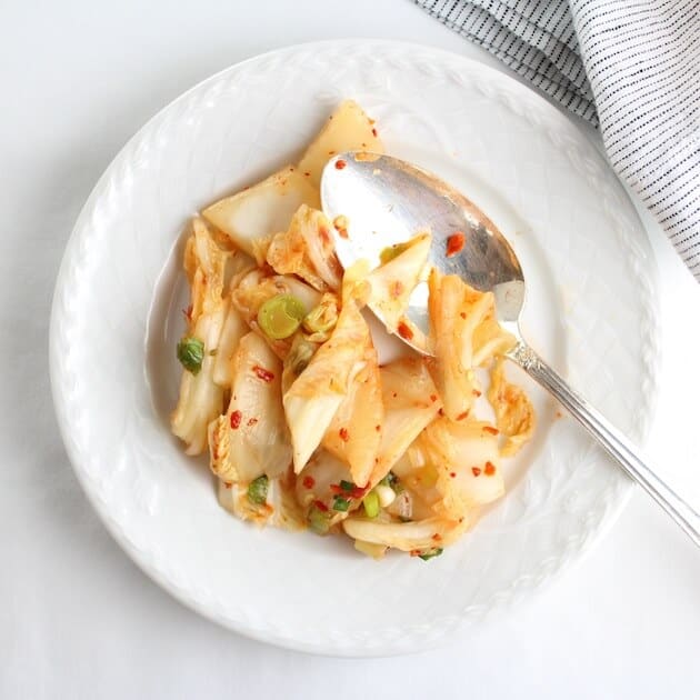 Homemade Kimchi on white plate with serving spoon