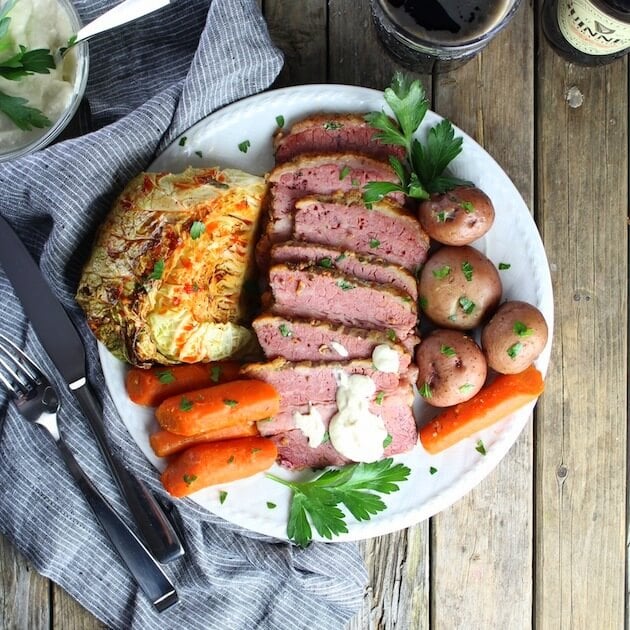 Full St. Patricks day Corned Beef And Cabbage meal on a plate with silverware and napkin