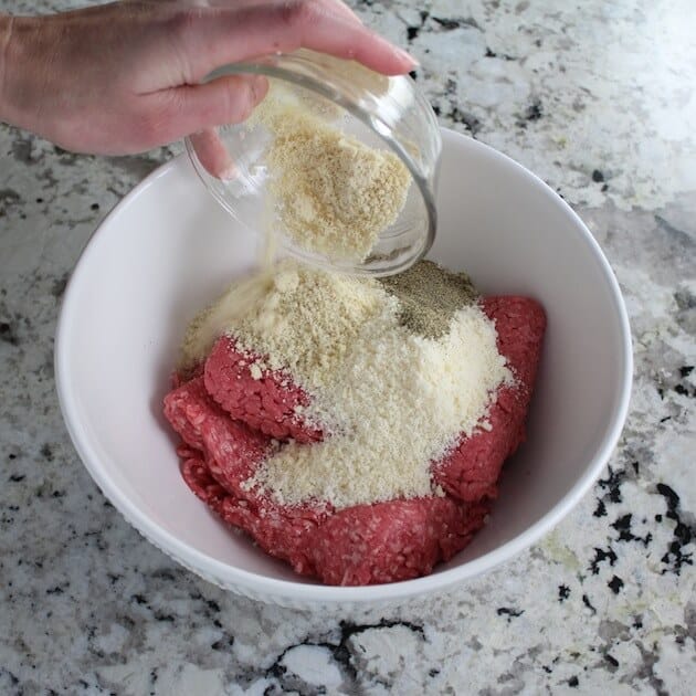 Adding seasonings to mixing bowl with meatball ingredients