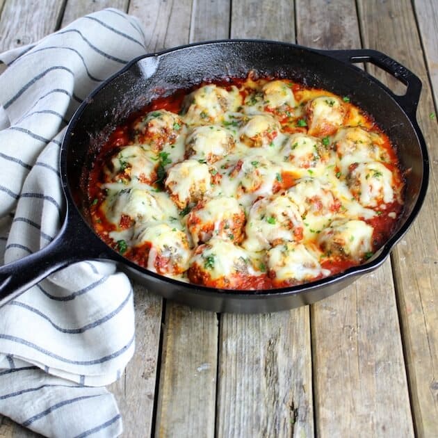 Italian Meatball smothered in melted cheese in cast iron skillet