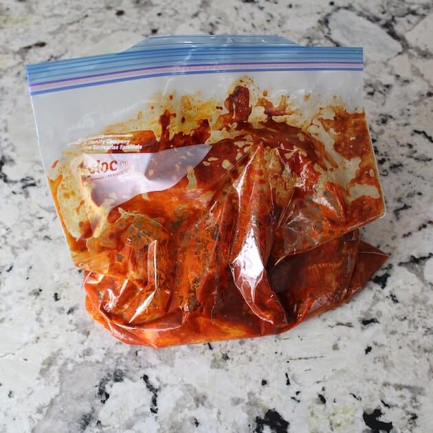 Sealed plastic bag with chicken in the red pepper marinade.