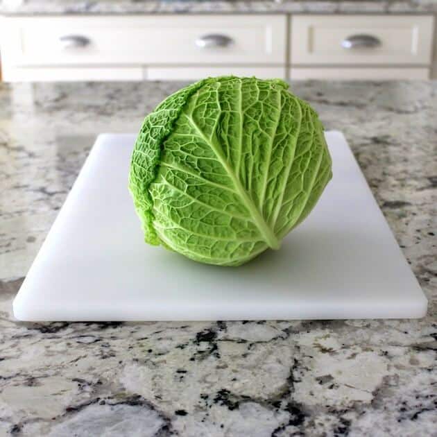 Beautiful bright green whole cabbage on cutting board in kitchen