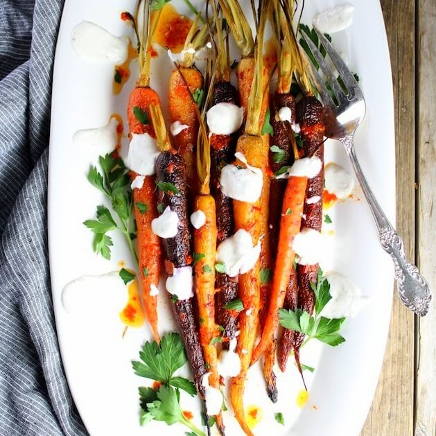 Honey Harissa Rainbow Carrots on a platter with yogurt