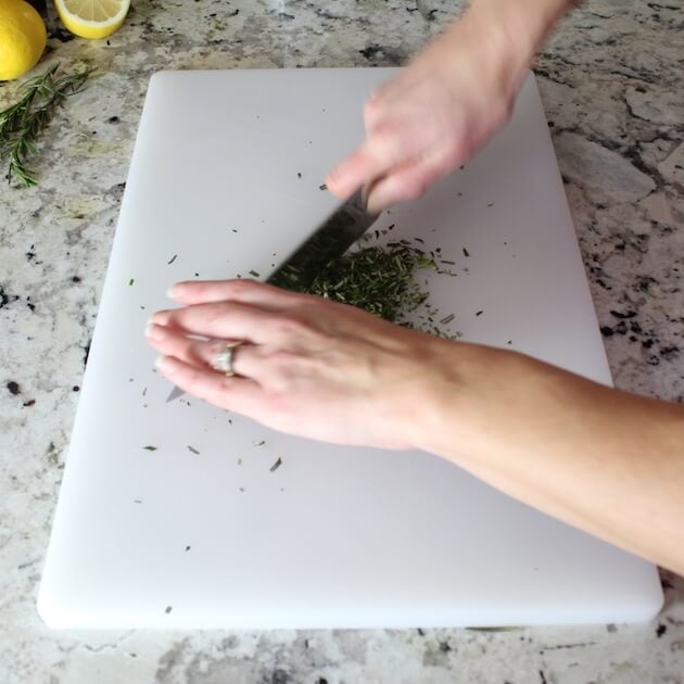 Chopping herbs on cutting board.