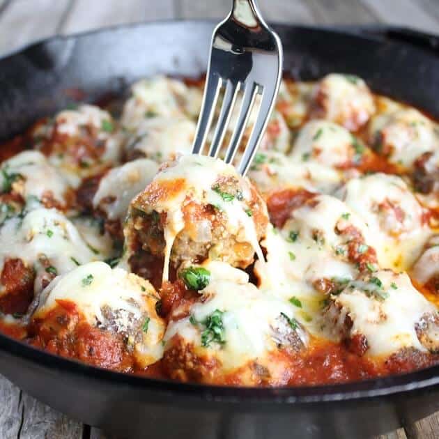 Fork lifting one Italian Meatball out of skillet 