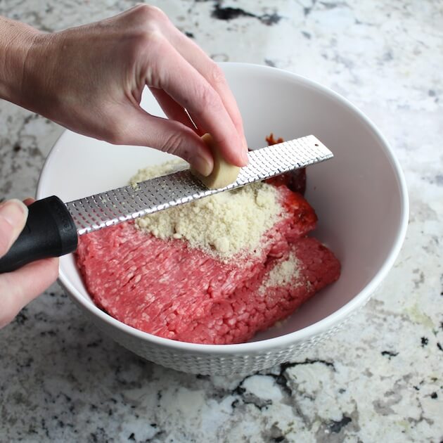 Zesting ginger into mixing bowl of ingredients for meatballs